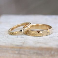 two gold wedding rings sitting on top of a wooden table