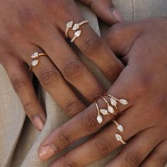 two people wearing gold rings with leaves on their fingers and one holding the other's hand