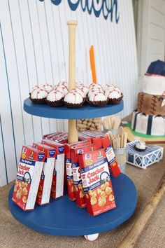 there is a cake and cupcakes on the blue plate at this baseball themed birthday party