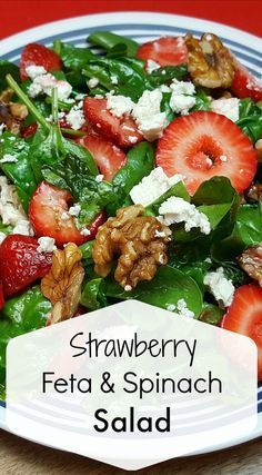 a salad with strawberries, feta and spinach on it in a blue and white plate