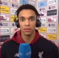 a young man wearing headphones and holding a microphone in front of a wall with signs