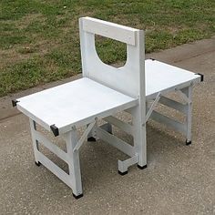 a white plastic chair sitting on top of a cement ground next to a green field