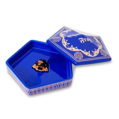 two blue dishes with gold designs on the lid and one has a piece of food in it