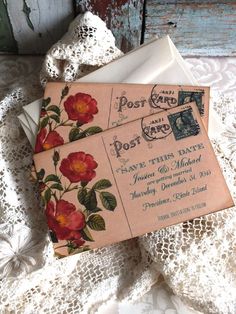 two envelopes are sitting on top of an old lace doily with flowers in them