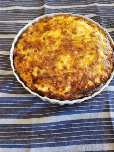 a cheesy dish sitting on top of a blue and white striped table cloth