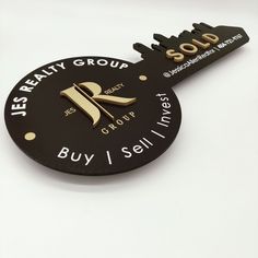 a keychain with a black and gold logo on it that says buy 1 sell 1 invest