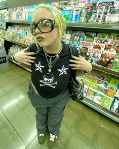 a woman wearing sunglasses and standing in front of a store shelf with her hands on her hips