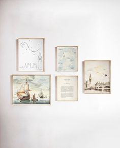 four framed pictures hang on the wall in front of a white wall with various drawings