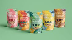 six bags of sprouted cashews are lined up on a green background