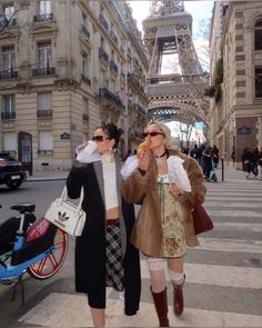 two women walking down the street in front of the eiffel tower