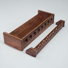 two pieces of wood with holes in the middle and one piece missing from it, sitting on a white surface