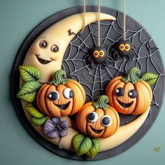 three pumpkins with faces hanging from strings on a circular wall decoration in front of a blue background