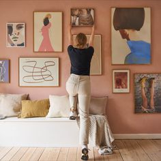 a woman is hanging pictures on the wall