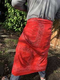 a man in grey shirt and red bandana skirt