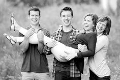 a group of people standing next to each other in a field with one holding a baby