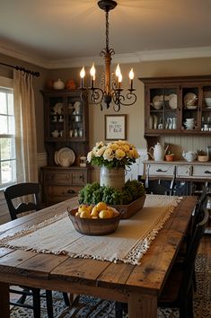 a wooden table topped with fruit and vegetables next to a light hanging from a chandelier