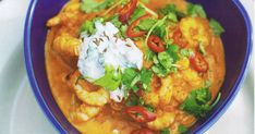 a blue bowl filled with food and garnished with sour cream on the top