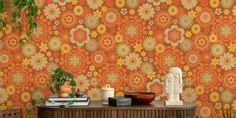 an orange and yellow floral wallpaper in a living room with two plants on the table