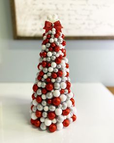 a red, white and grey christmas tree made out of plastic balls on a table