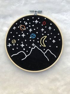 a black and white embroidery with stars, planets and the moon on it's back