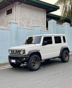 a white jeep parked in front of a blue wall