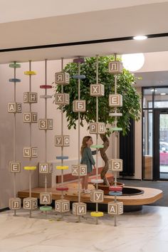 a woman standing next to a tree with letters on it