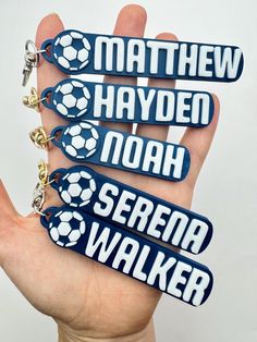 four keychains with soccer balls on them are in the palm of a person's hand