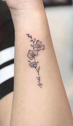 a small flower tattoo on the left side of the arm is shown in black ink