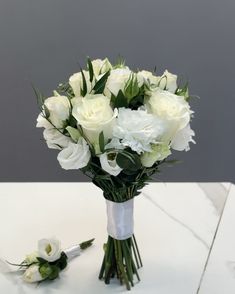 a bouquet of white flowers sitting on top of a table next to a boutonnier