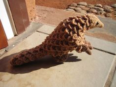 a crocheted seahorse sitting on the ground next to a door way with rocks in the background