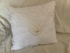 a white lace pillow with a button on the front and an envelope in the back