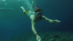 a woman is swimming in the water with her feet on the ground and wearing goggles