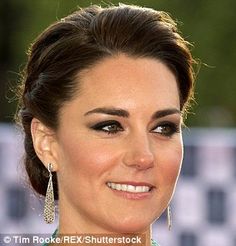 a close up of a person wearing earrings and a green dress smiling at the camera