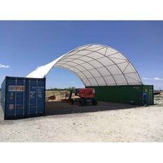 a large white tent sitting on top of a dirt field next to a fork lift