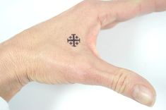 a person's hand with a small cross tattoo on it