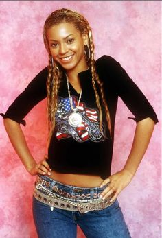 a woman with long braids standing in front of a pink background