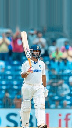 a man holding a cricket bat on top of a field in front of a crowd