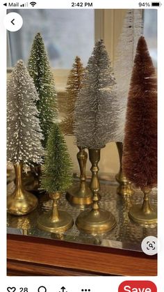 christmas trees are displayed in gold and silver vases on a glass counter top with the price tag below them