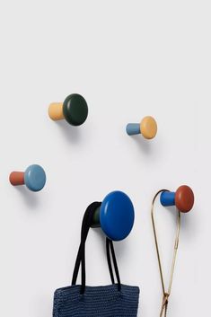 an assortment of colorful knobs and handles on a white wall with a blue bag