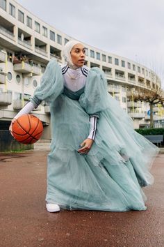 a woman in a blue dress holding a basketball