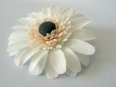 a white flower with black center sitting on top of a table