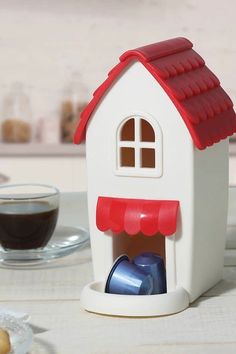 a small toy house with a cup of coffee in front of it on a table