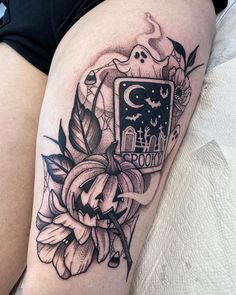 a woman's thigh with a black and white tattoo design on it, including flowers