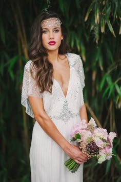 a woman in a white dress holding a bouquet and wearing a headpiece with flowers