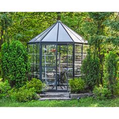 a gazebo in the middle of some bushes and trees with a bicycle on it