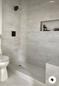 a white toilet sitting in a bathroom next to a walk in shower and tiled walls