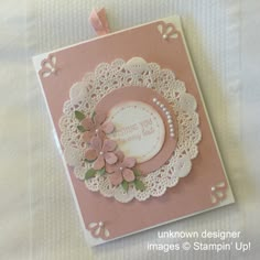 a pink card with white doily and flowers on it