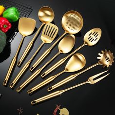 gold colored kitchen utensils are arranged on a black surface