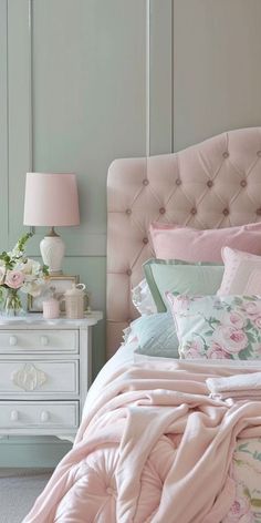 a bed with pink comforter and pillows in a bedroom next to a white dresser