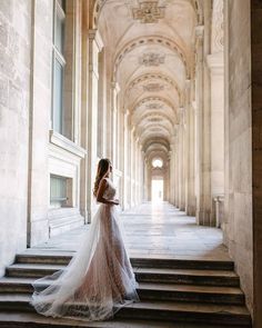 a woman in a wedding dress is standing on some stairs and looking off into the distance